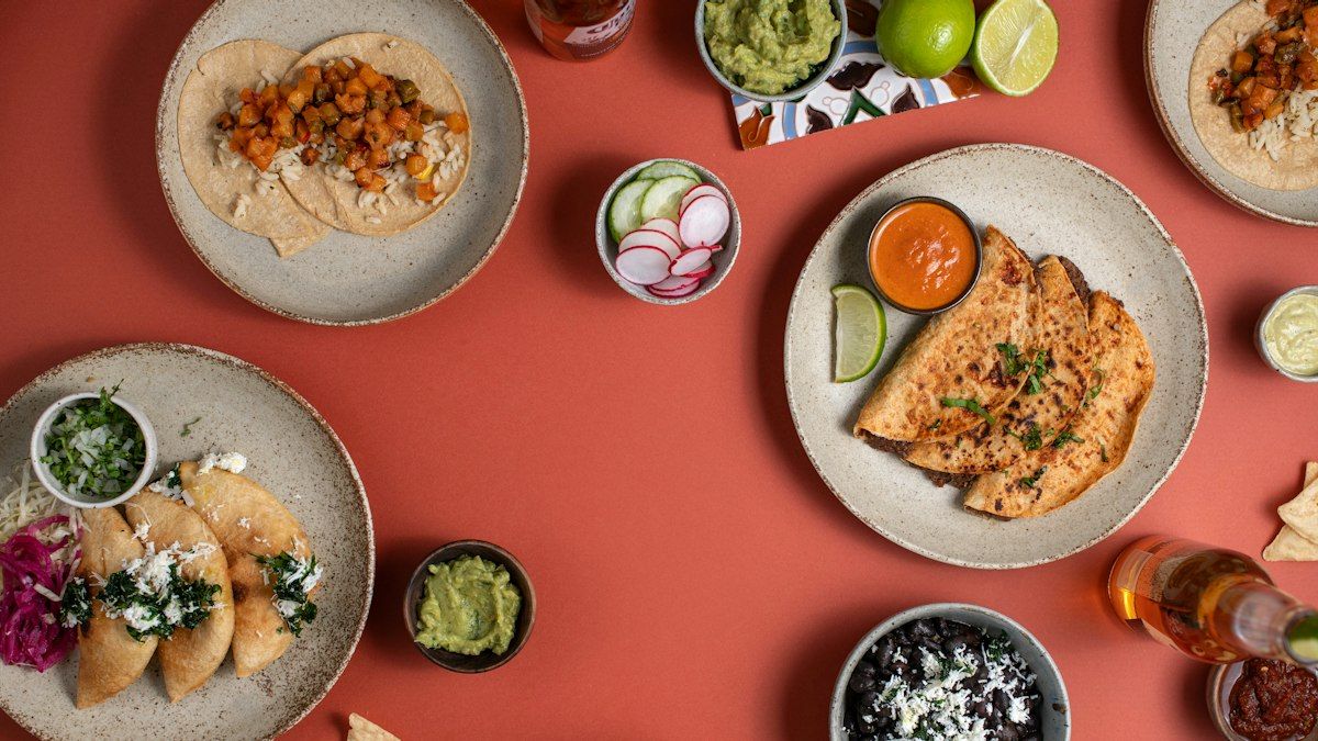 Bowls of shredded chicken, avocado, pico de gallo, and warm tortillas on a board