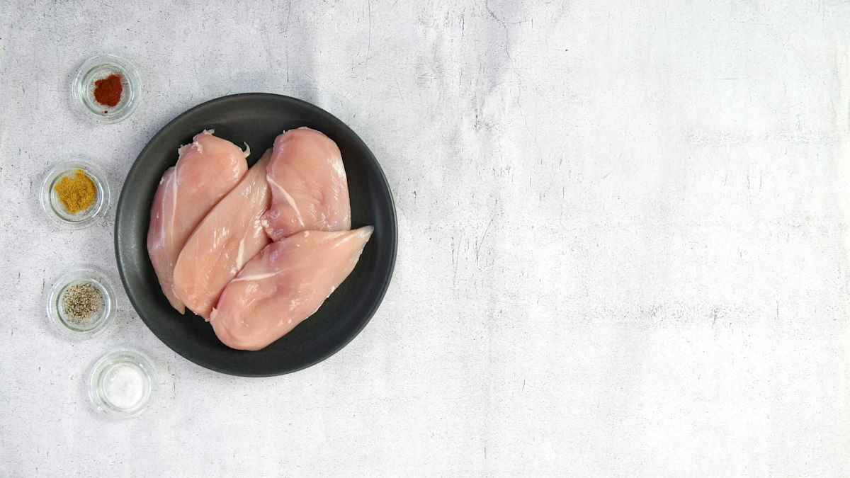 Fresh chicken thighs seasoned with aromatic herbs and spices on a cutting board