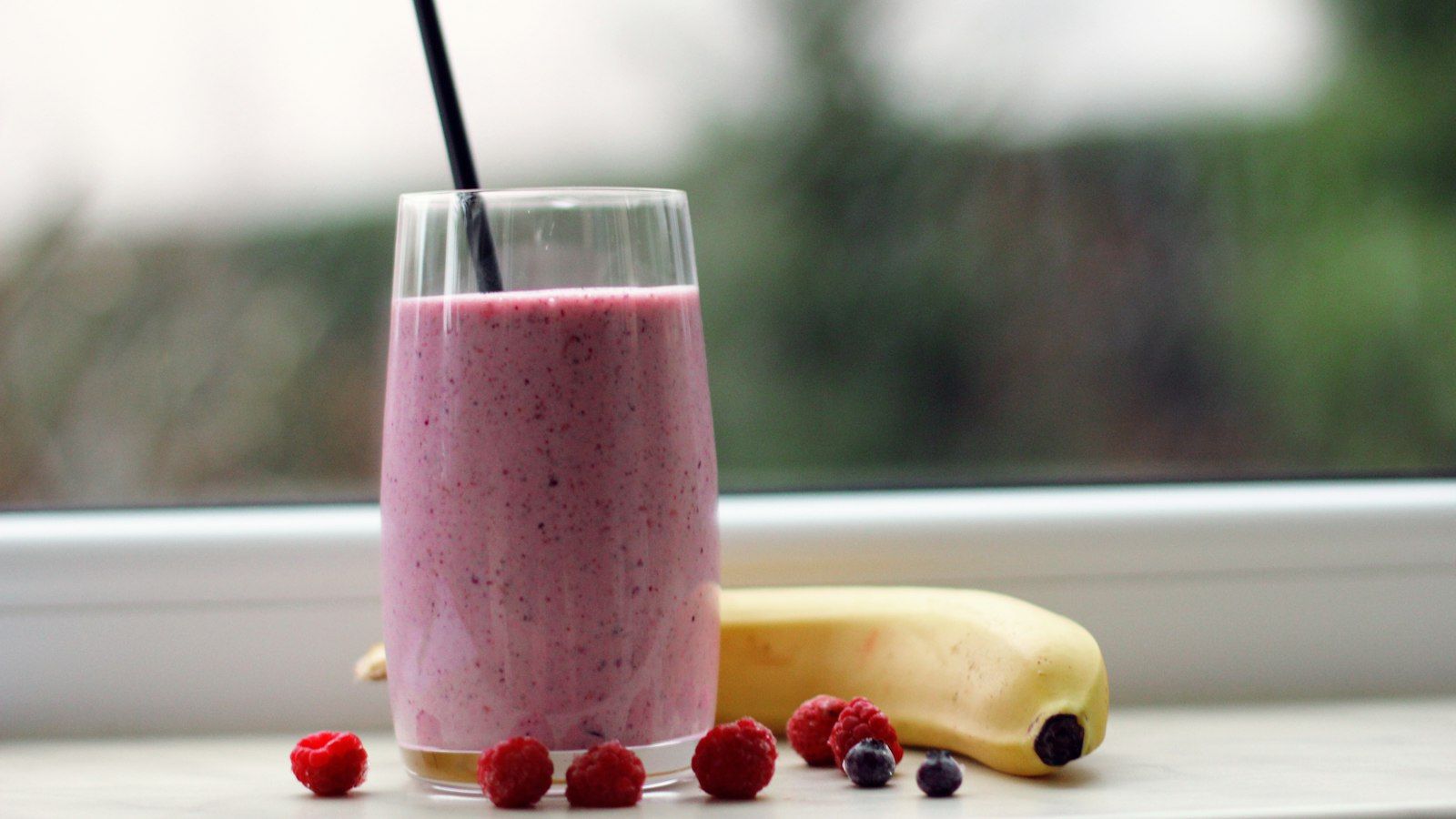 A vibrant berry smoothie made with frozen fruit and yogurt served in a tall glass