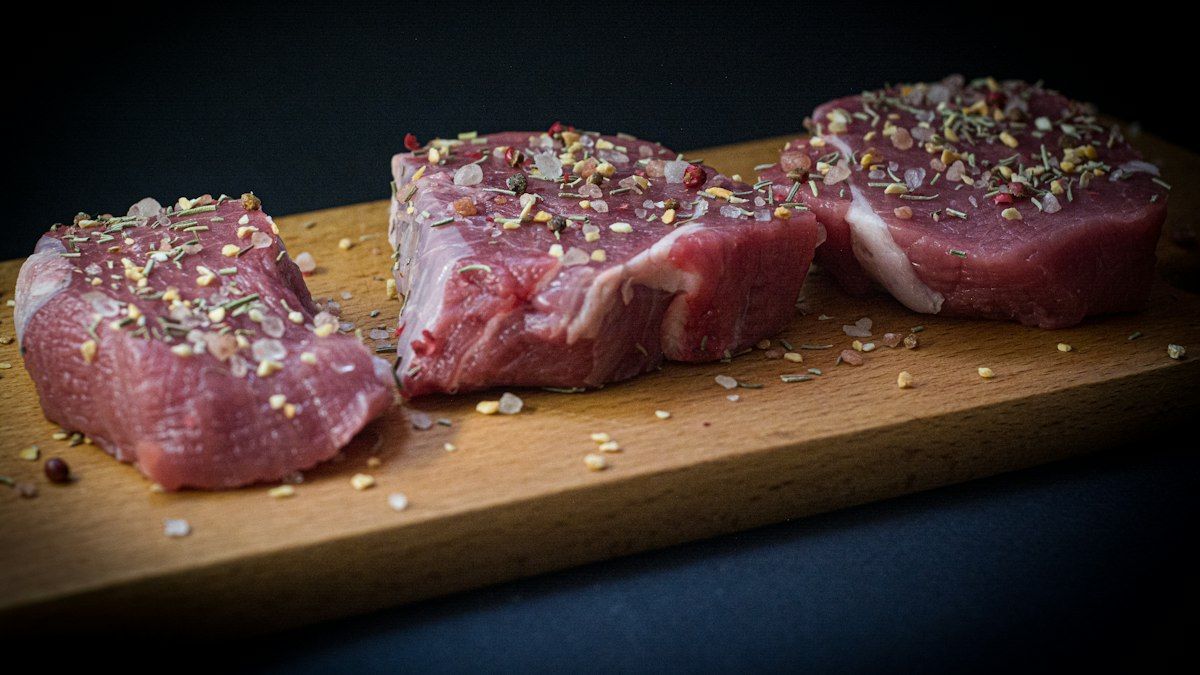 Thick cut raw pork chops seasoned with herbs and garlic on cutting board