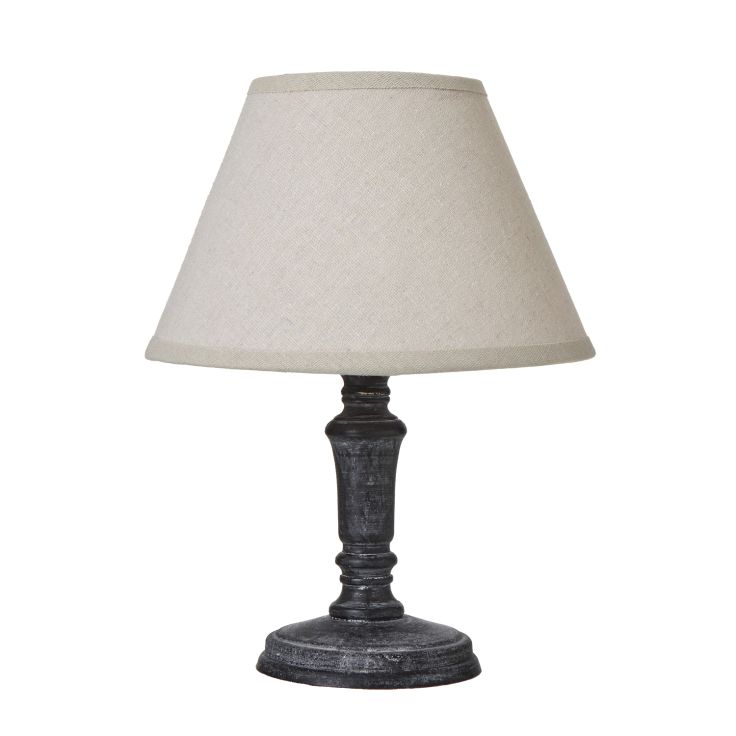 Palmyra Column Table Lamp with a distressed black base and neutral linen shade displayed on a side table.
