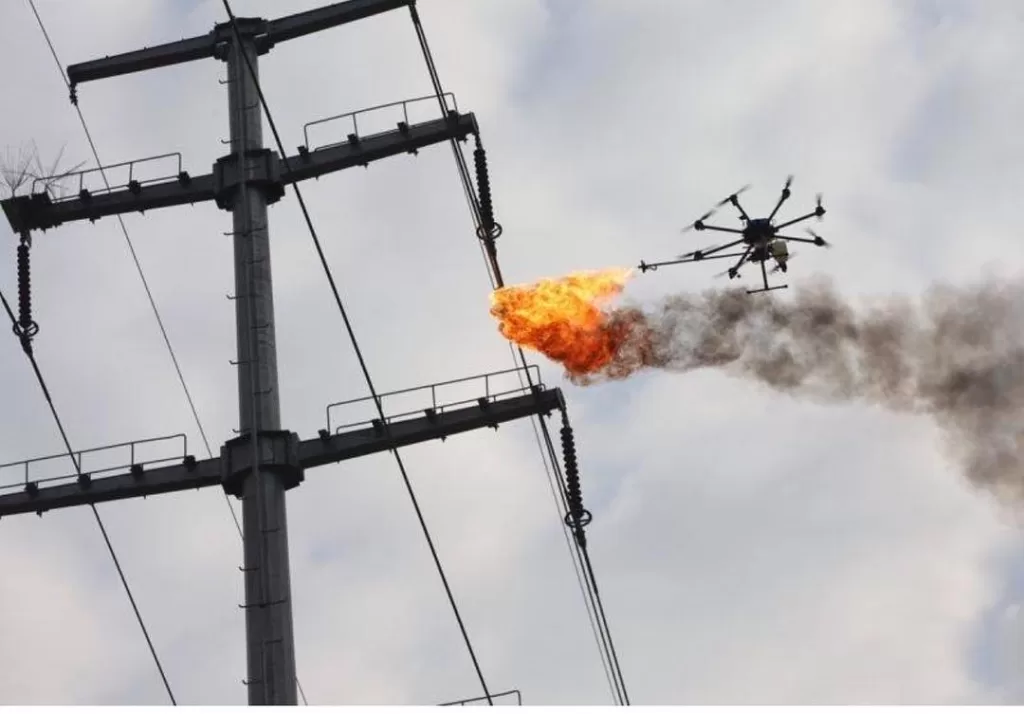 Drone incendiario realizando la incineración de un trozo de plástico atrapado en una línea de transmisión eléctrica