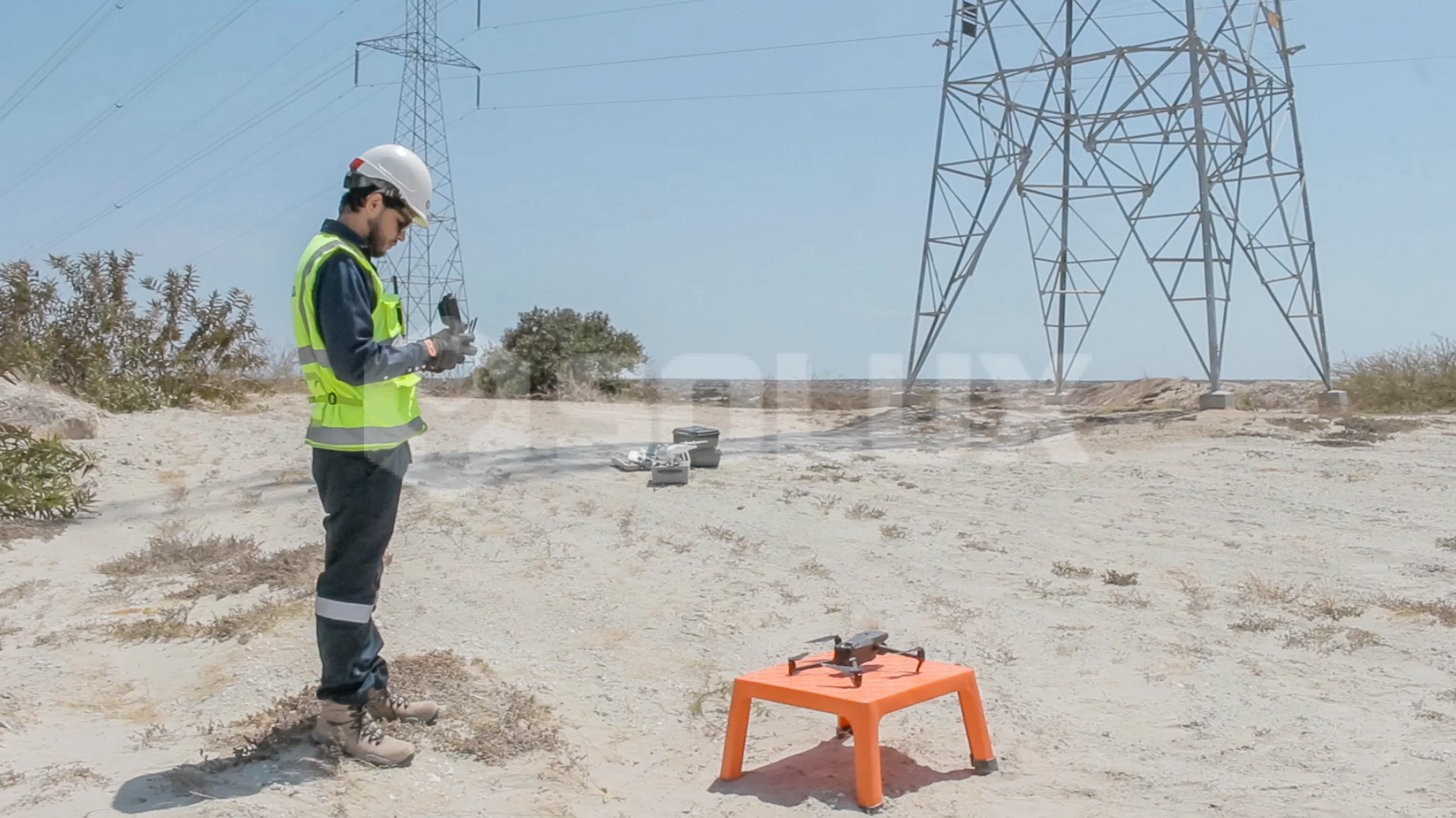 Piloto de dron realizando las comprobaciones antes de sobrevolar una torre de transmisión eléctrica.