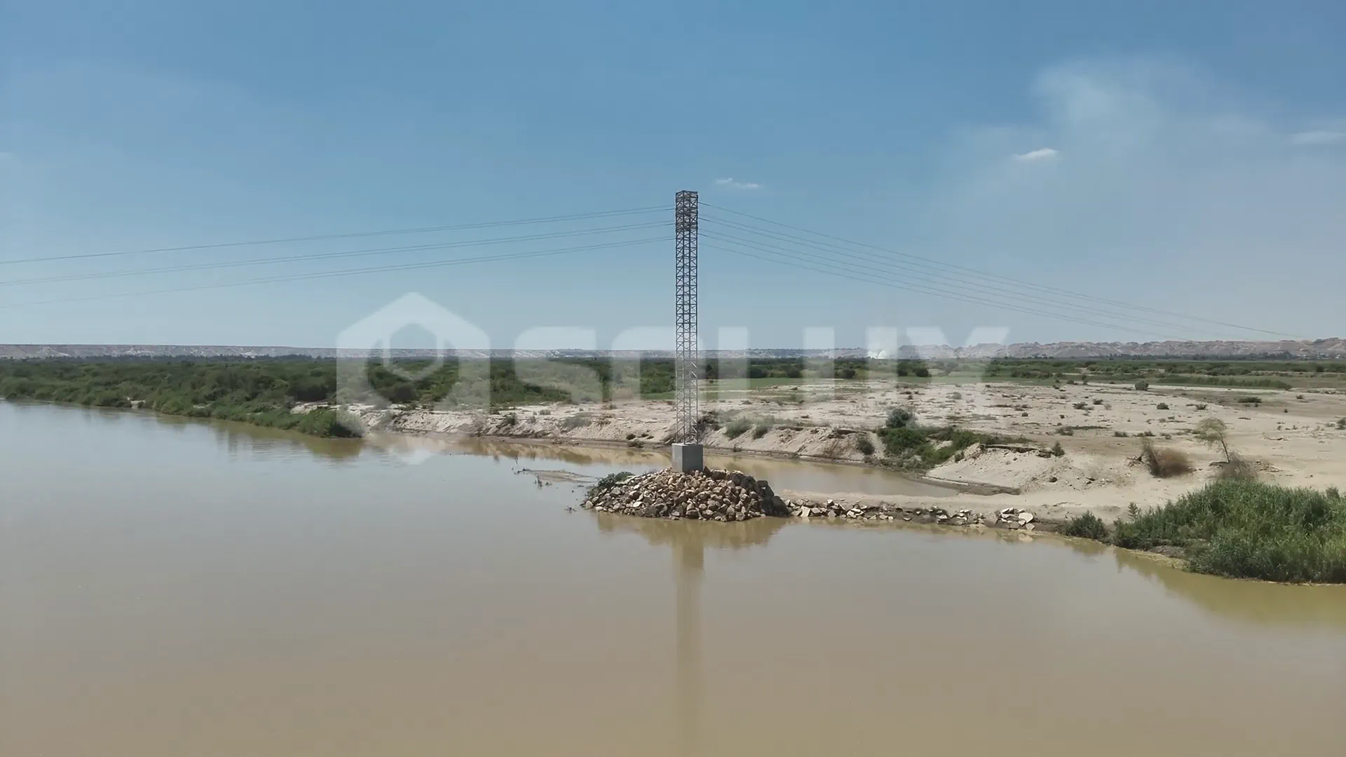 Estructura de distribución eléctrica de 22.9kV al costado de un río.