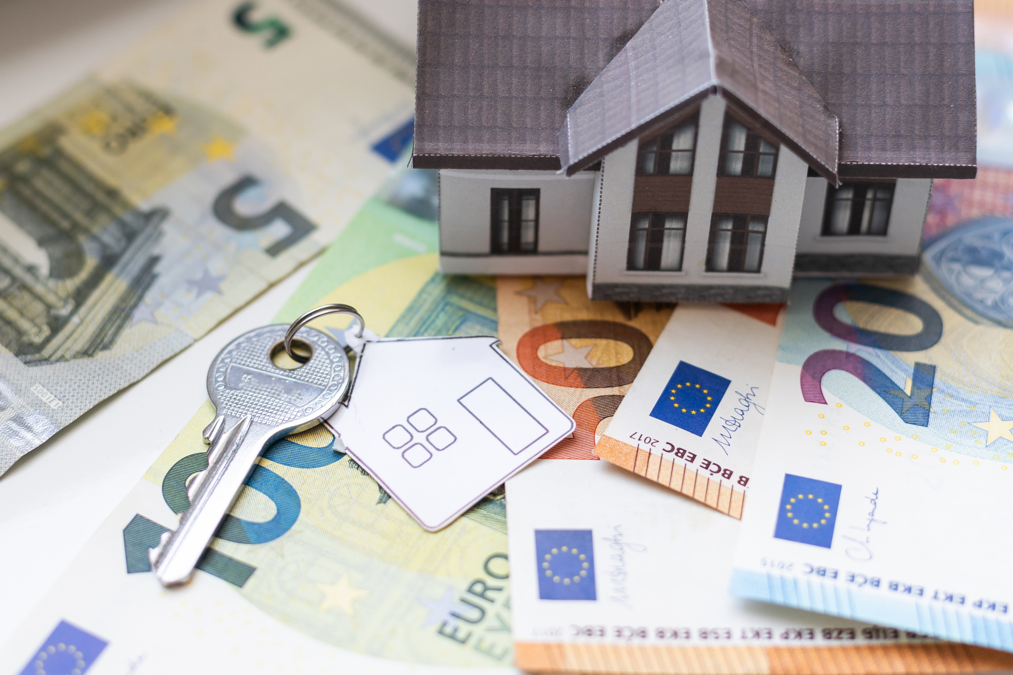 Eigenkapital: Auf mehreren Geldscheinen steht das Model eines Hauses