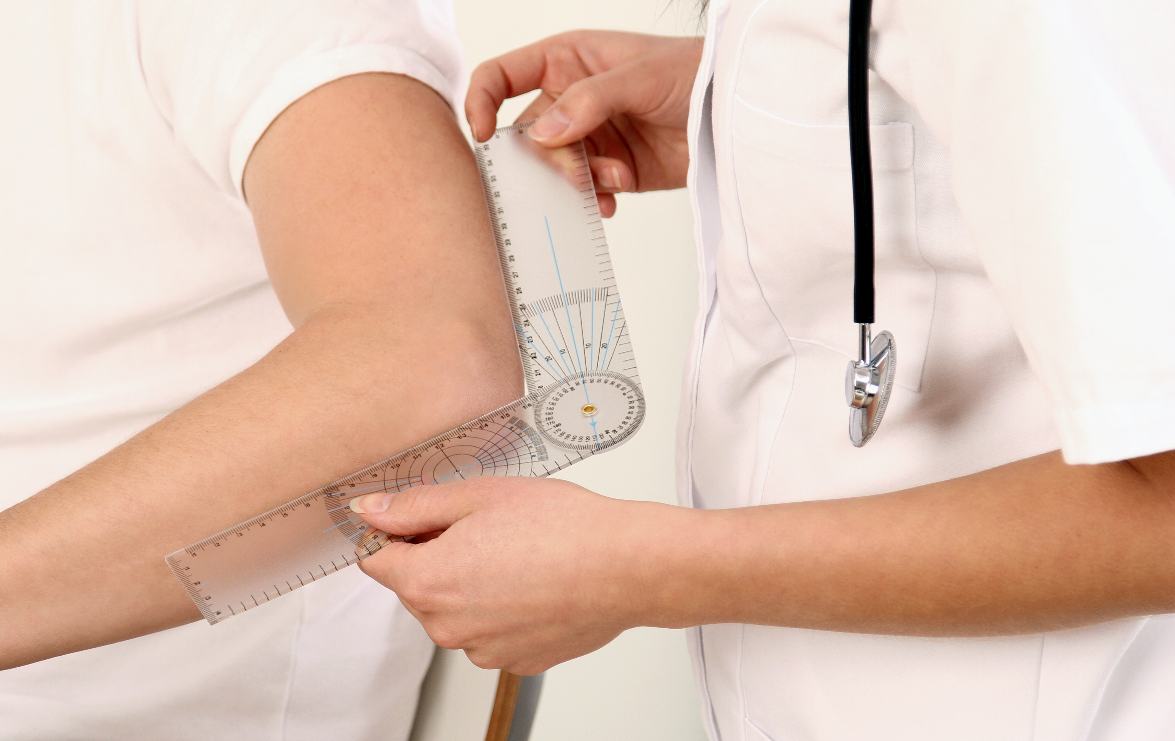 Orthopäde misst Ellenbogen von Patienten mit Instrument aus