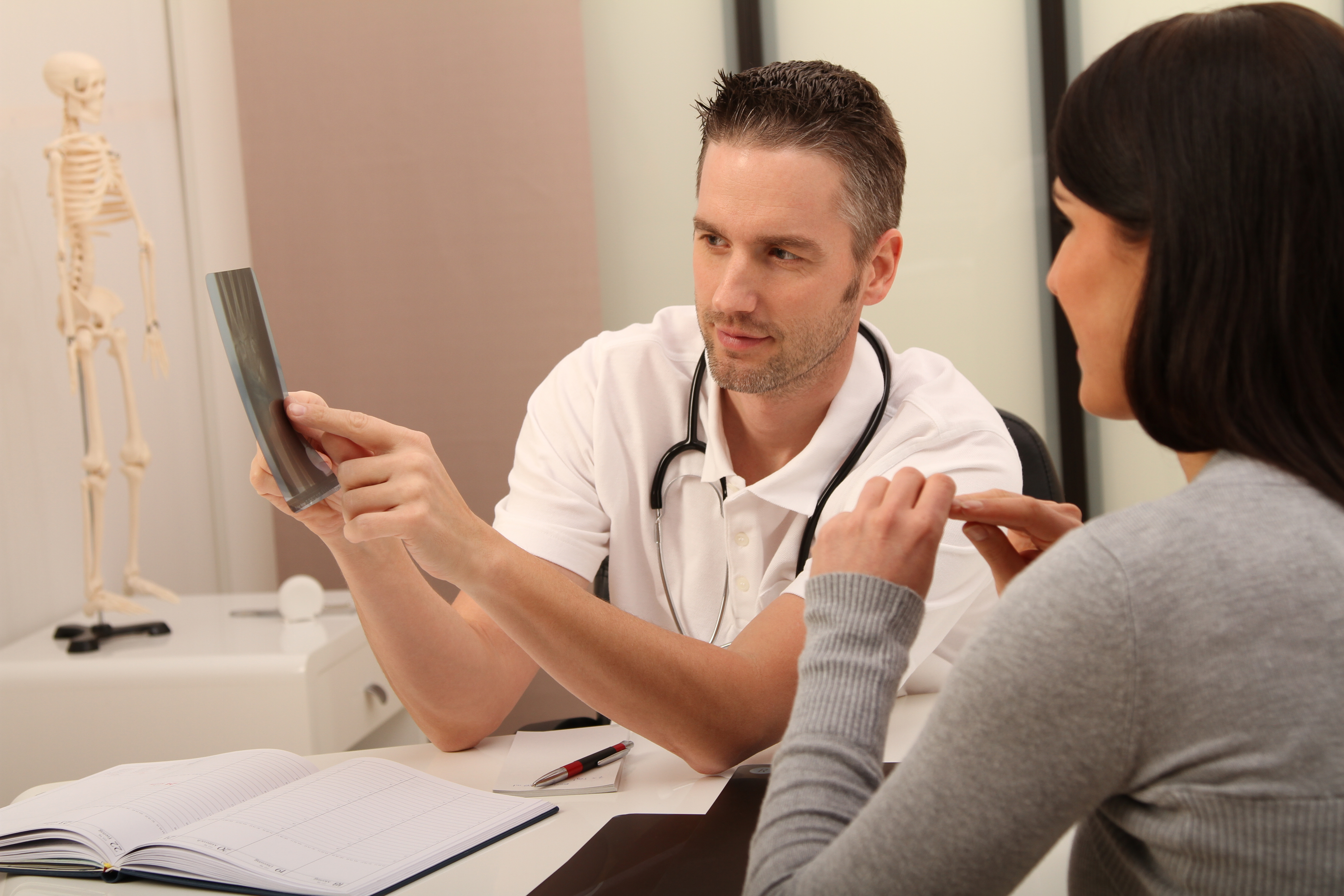 Orthopäde erklärt einer Patienten ein Röntgenbild von ihrem Rücken
