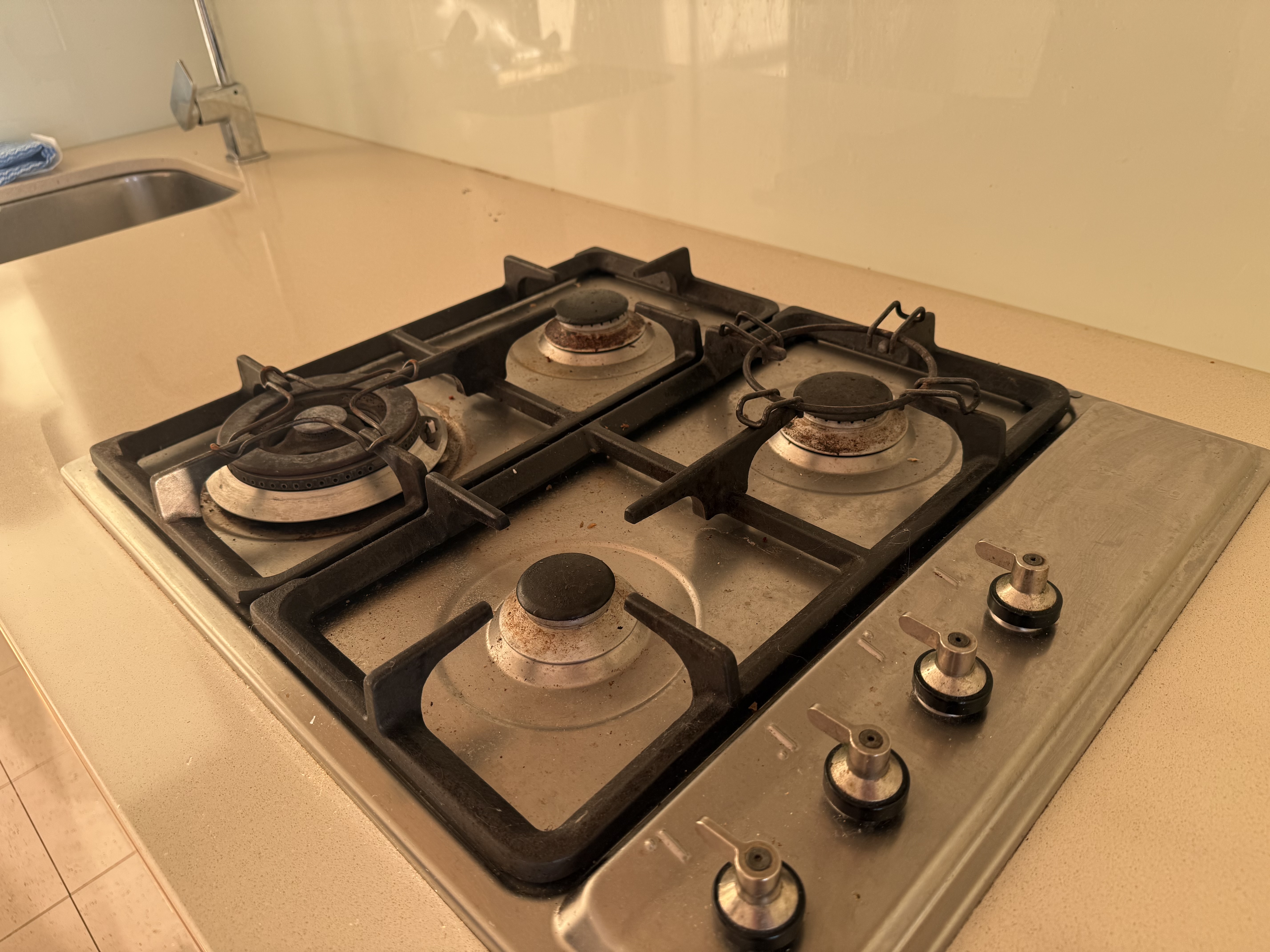 Kitchen cooktop before end of lease clean — greasy grates