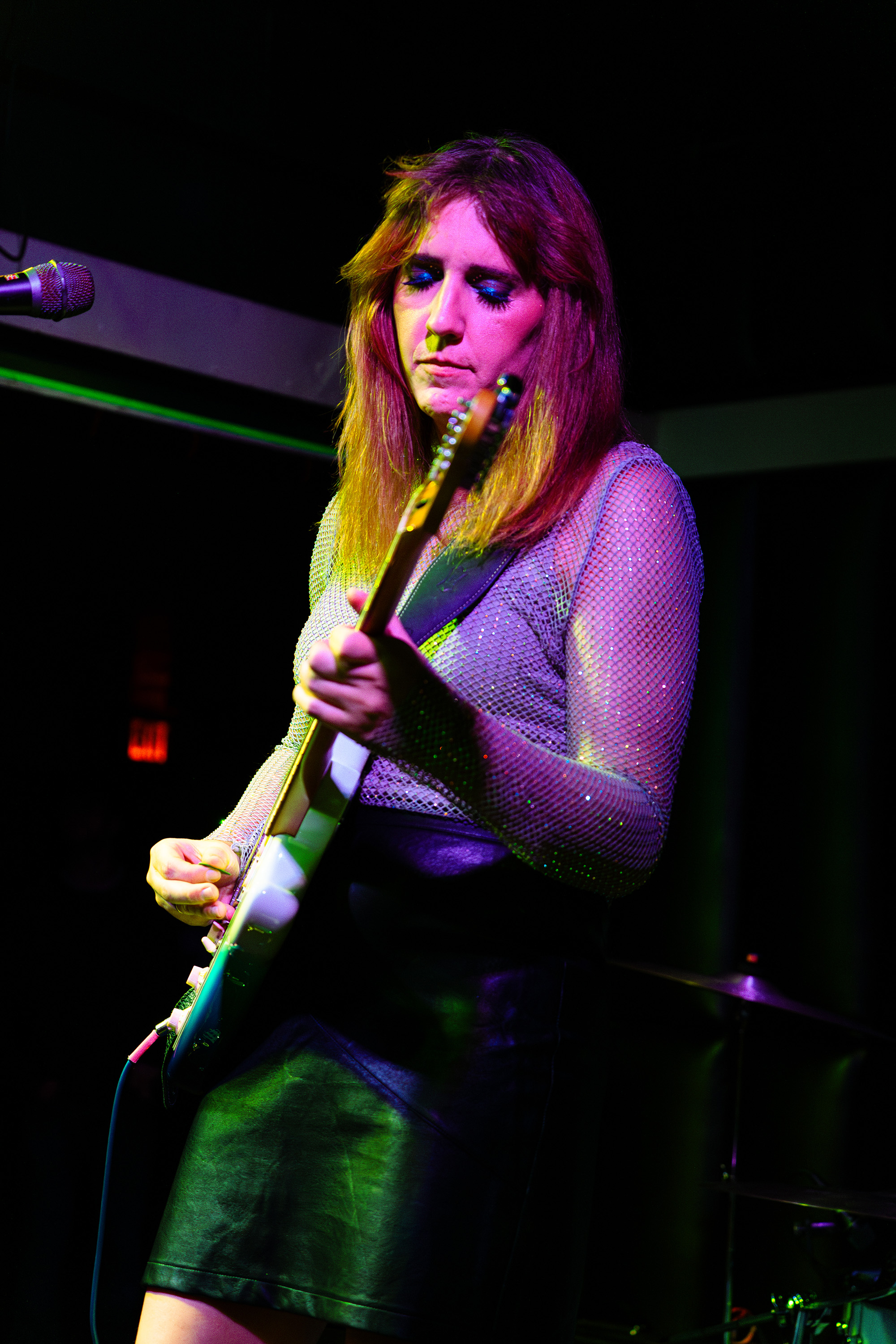 Mariela standing on a stage singing and playing her guitar.
