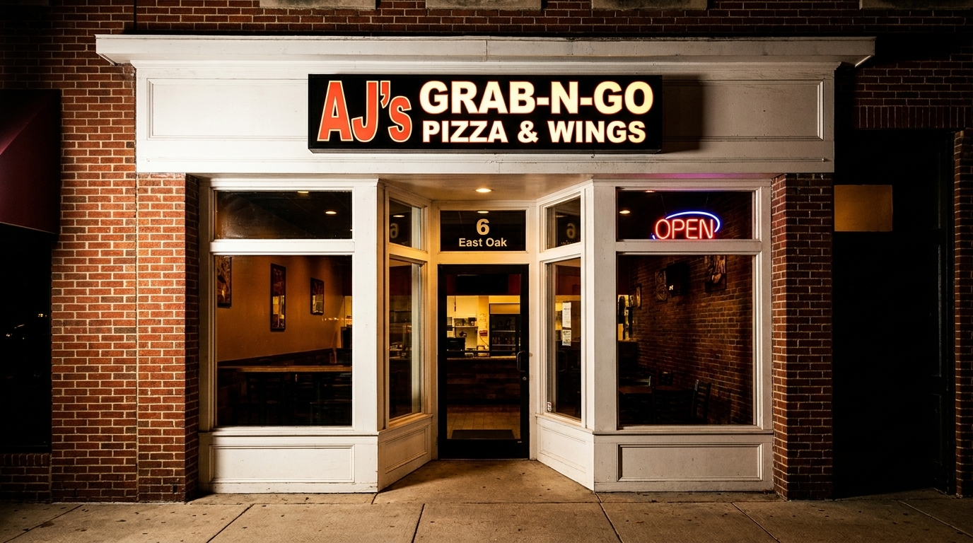 Exterior of AJ's Grab-N-Go Pizza & Wings, a brick building with a glowing "OPEN" sign.