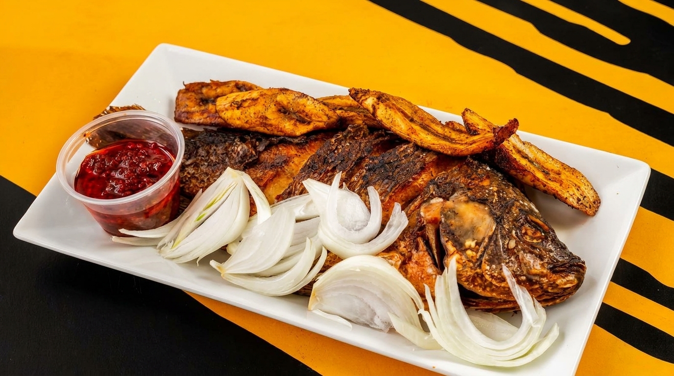 Grilled whole fish with plantains, sliced onions, and a side of red pepper sauce.
