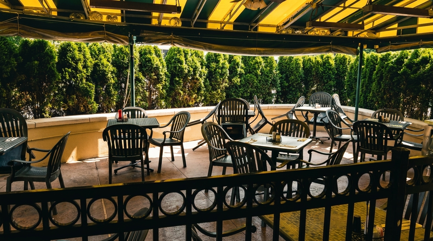 Outdoor patio dining area with dark tables and chairs under a yellow and green striped awning.