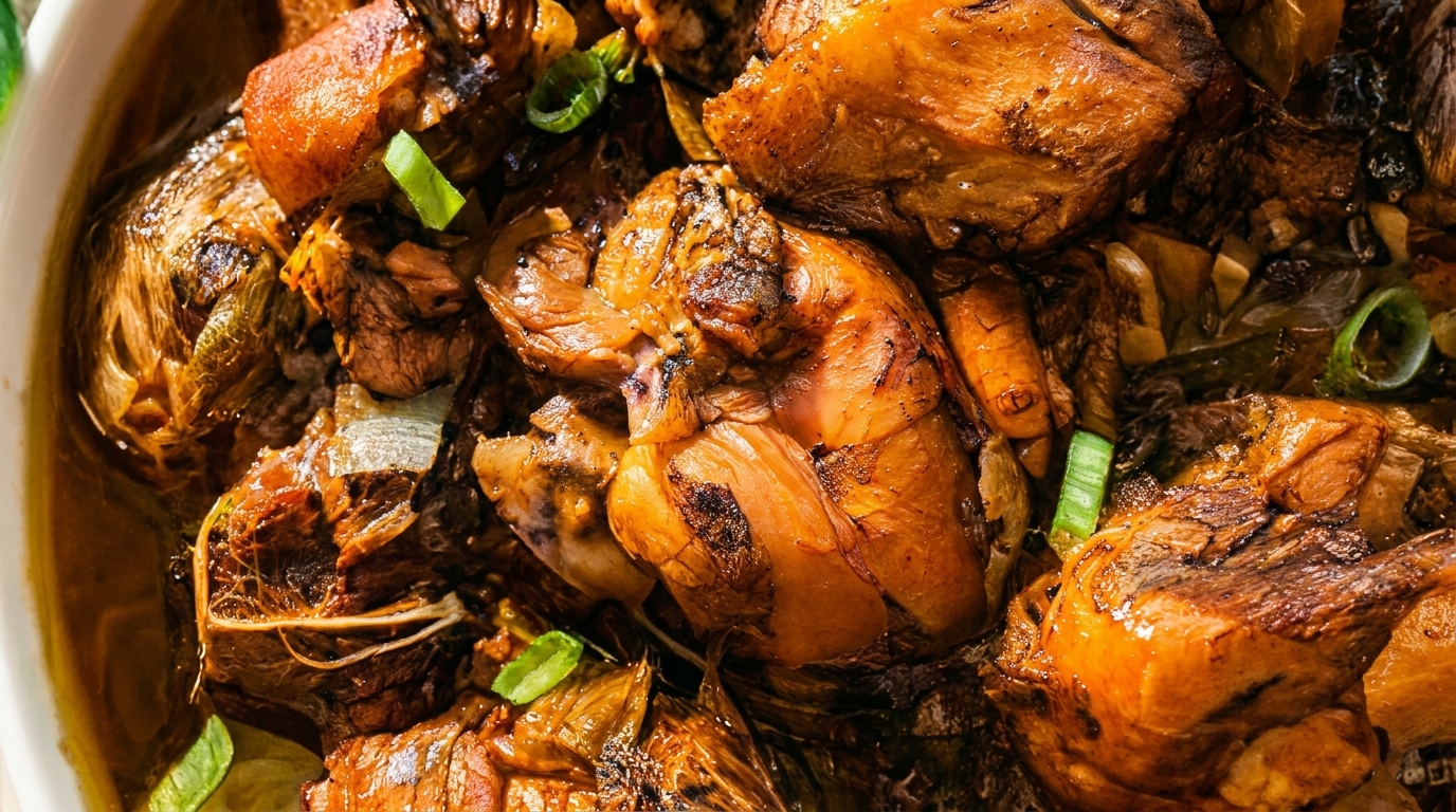 Close-up of braised chicken and vegetables in a rich, dark sauce, garnished with green onions.