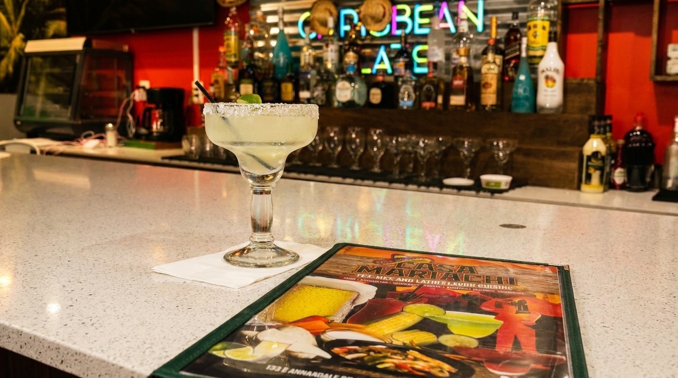 A margarita and menu on a bar counter with liquor bottles and neon signs in the background.