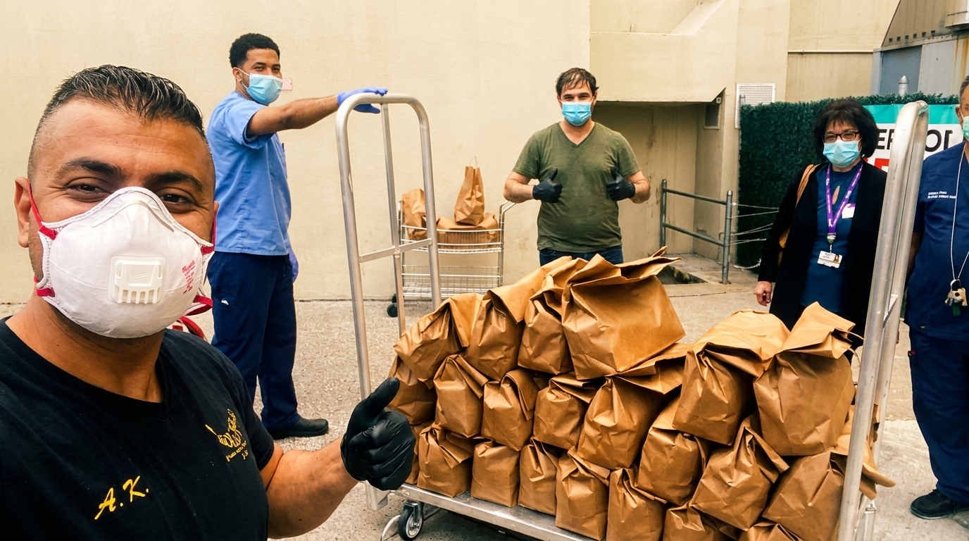 People in masks and gloves stand with carts full of brown paper bags of food.