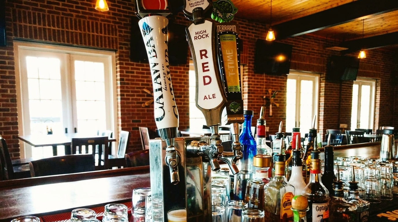 Beer taps and liquor bottles on a bar counter with brick walls and sunlit windows.