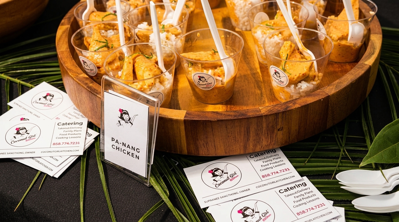 Mini cups of Coconut Girl Kitchen's Pa-Nang Chicken with rice, spoons, and business cards.