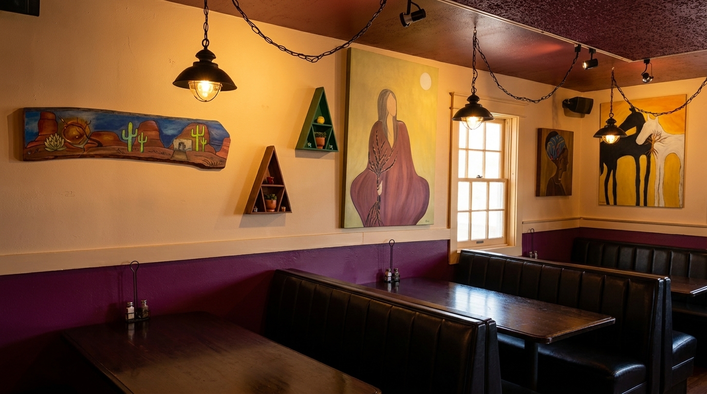 Restaurant interior with booth seating, hanging lights, and colorful artwork on cream-colored walls.