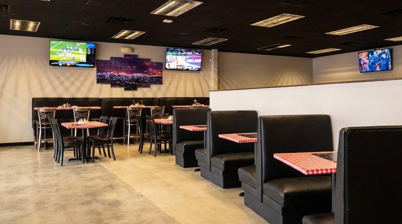 Restaurant interior with black booths, checkered tablecloths, high-top tables, and multiple TVs showing sports.