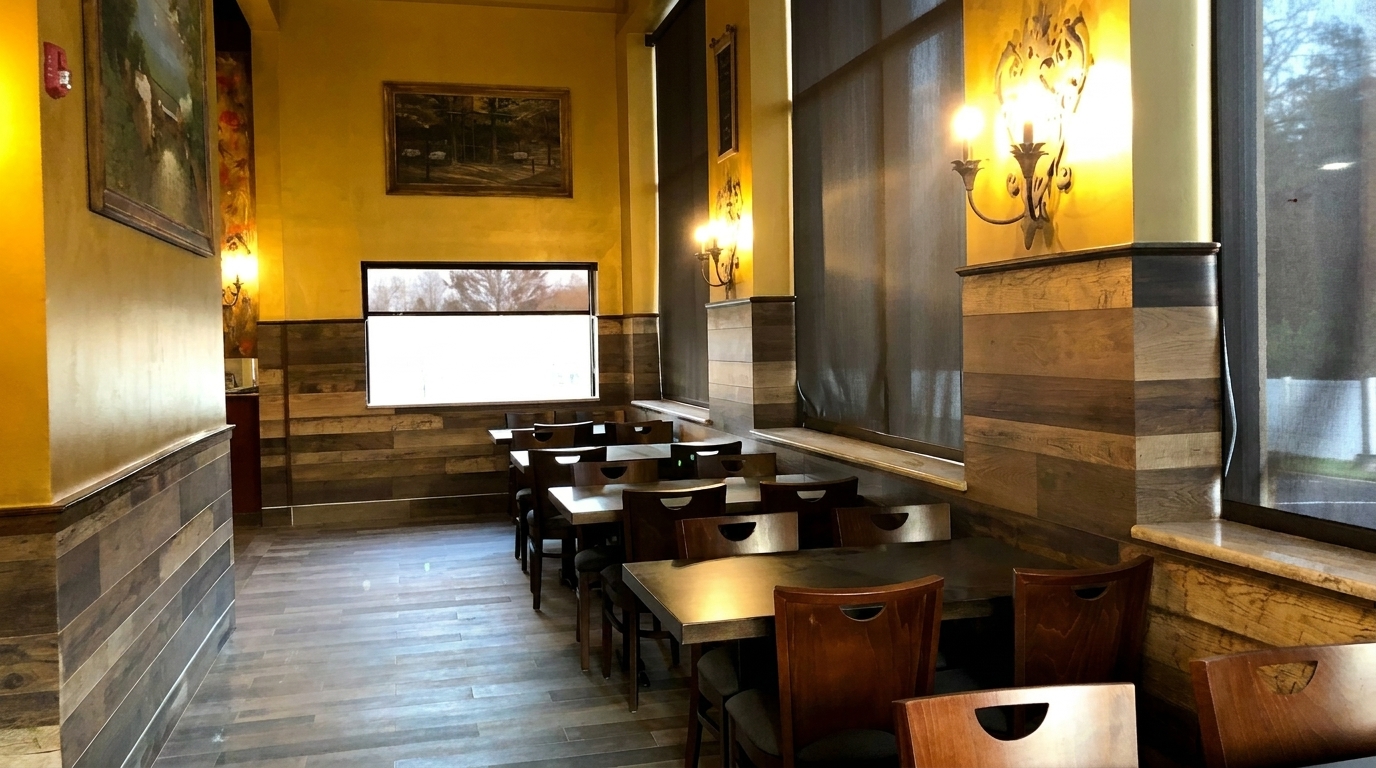 Empty restaurant dining room with yellow walls, wood paneling, dark tables, and chairs.