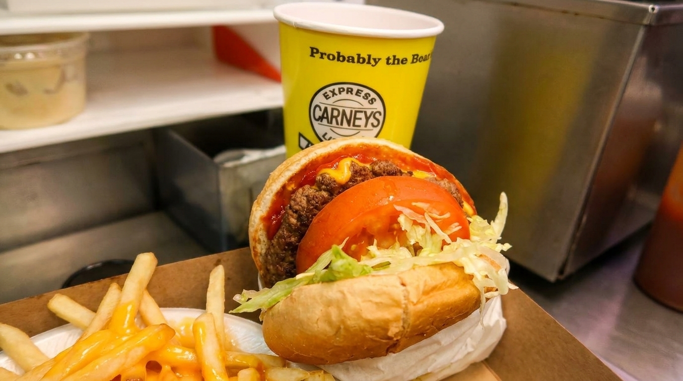 Carney's burger with tomato and lettuce, cheese fries, and a yellow Carney's cup.