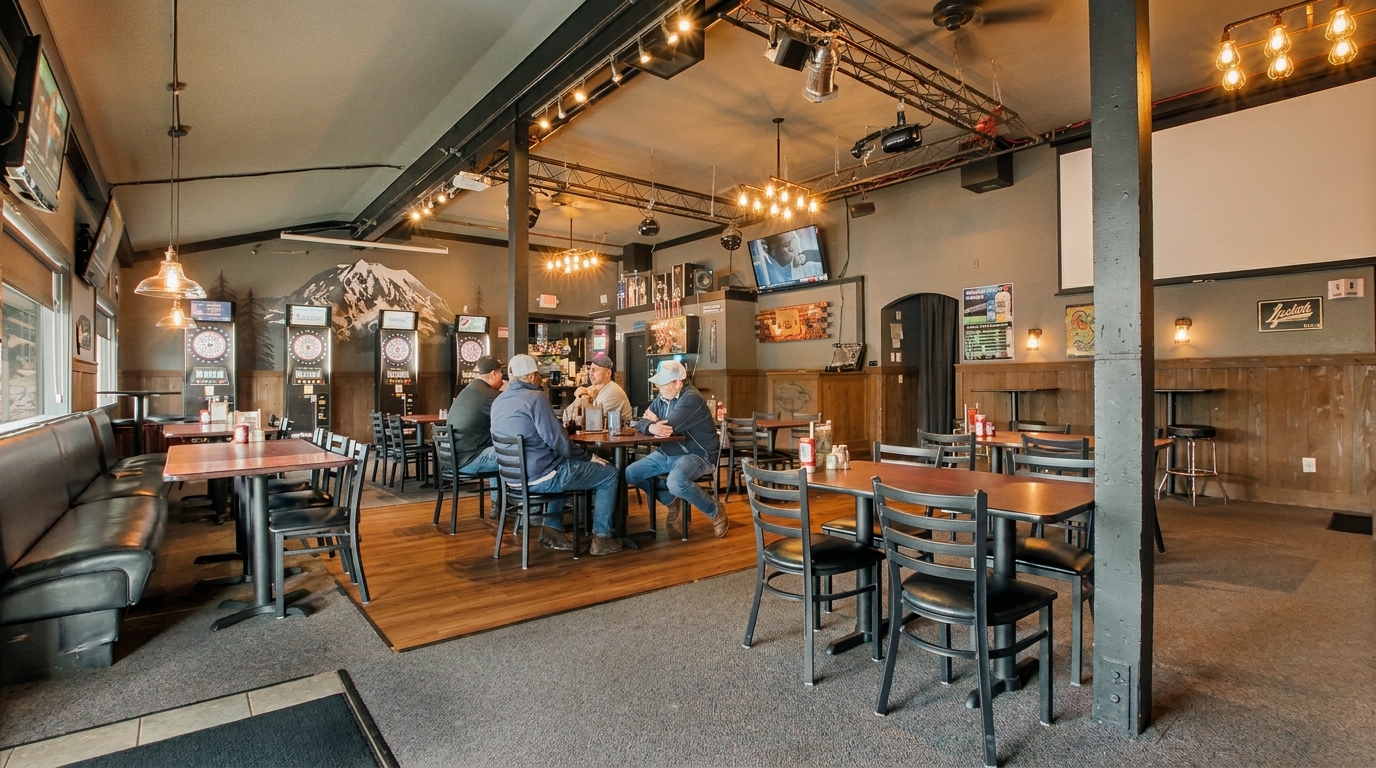 A casual restaurant interior with patrons at tables, dartboards, and a mountain mural on the wall.
