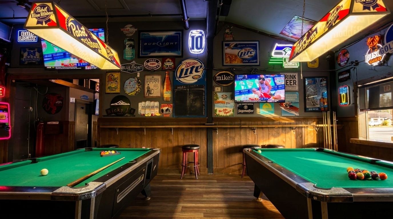 Two pool tables under beer-branded lights in a dimly lit bar with neon signs and TVs.