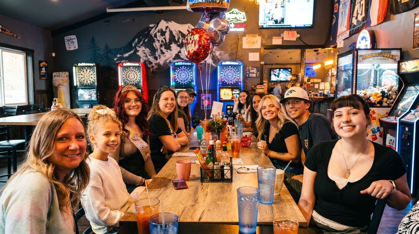 A group of smiling people, including adults and children, seated around a long wooden table in a lively restaurant.