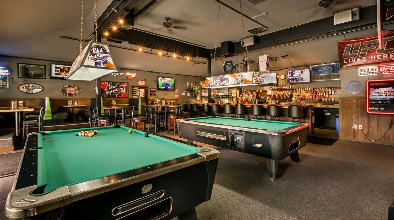 A lively bar interior with two pool tables, a fully stocked bar, and sports memorabilia.