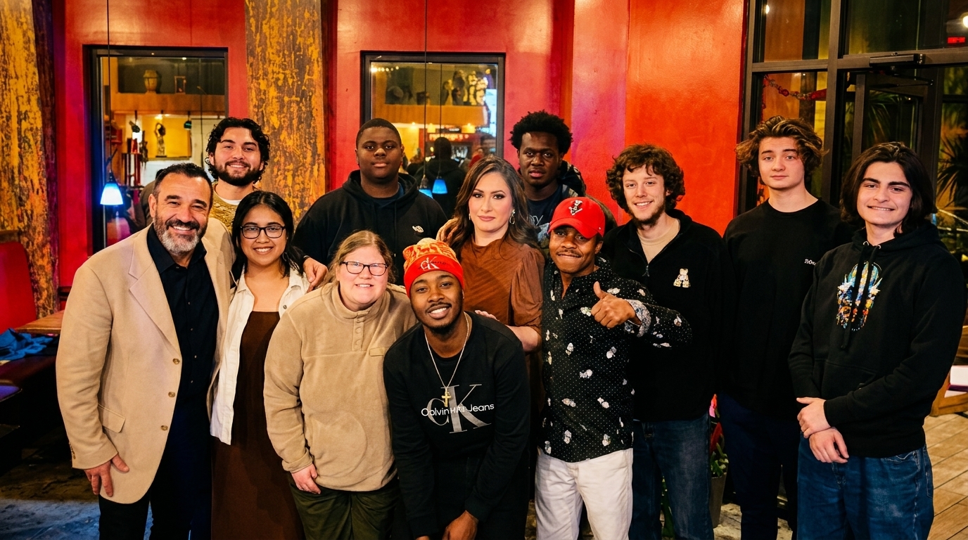 A large group of diverse people smiling for a photo inside a restaurant with red walls.