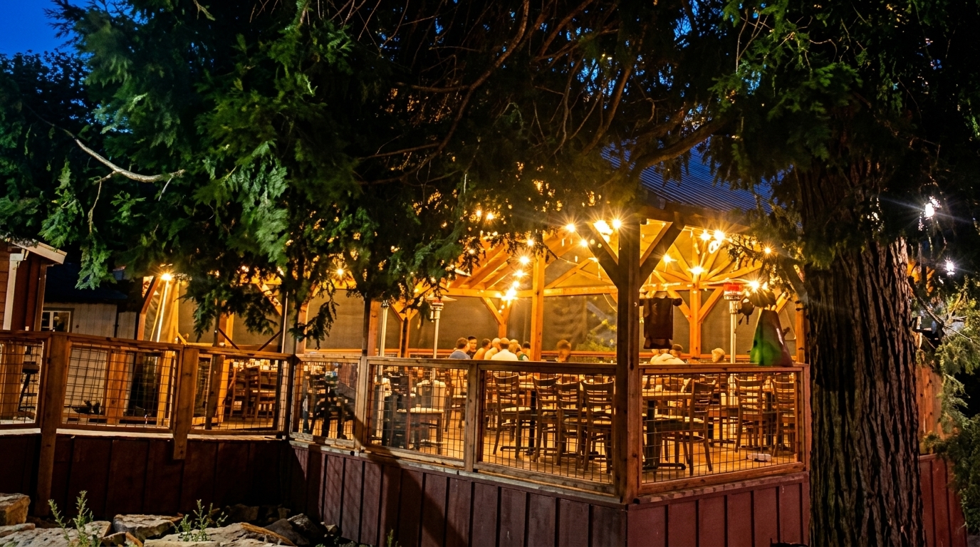 Outdoor restaurant patio at night, illuminated by string lights, with people dining at tables.