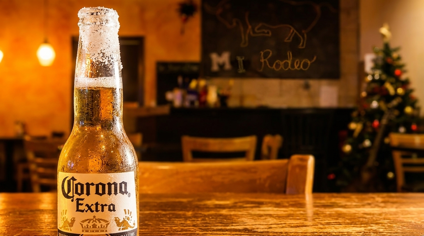 Salt-rimmed Corona Extra beer bottle on a wooden table in a restaurant with a Christmas tree.