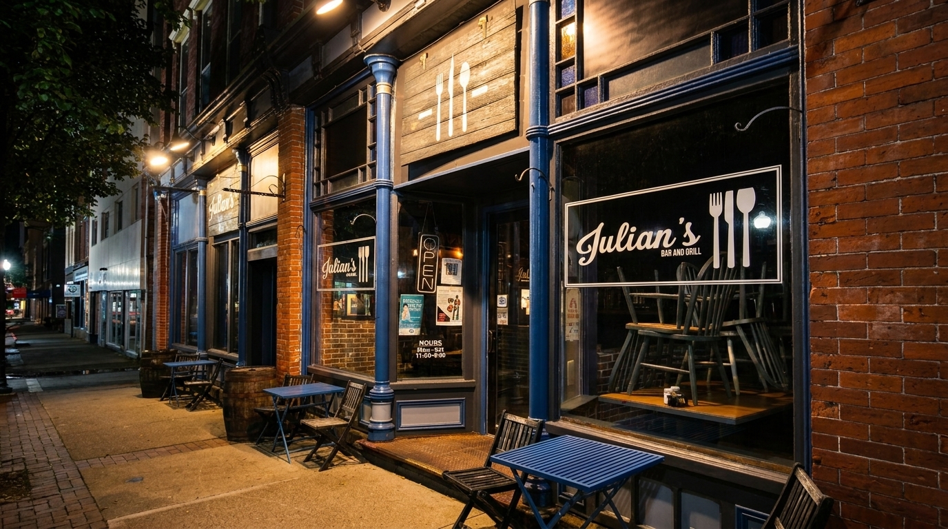 Julian's Bar and Grill exterior at night, with blue tables and chairs on the sidewalk.