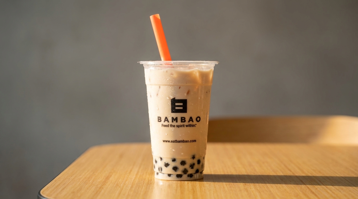 Bambao bubble tea with an orange straw on a wooden table against a gray background.