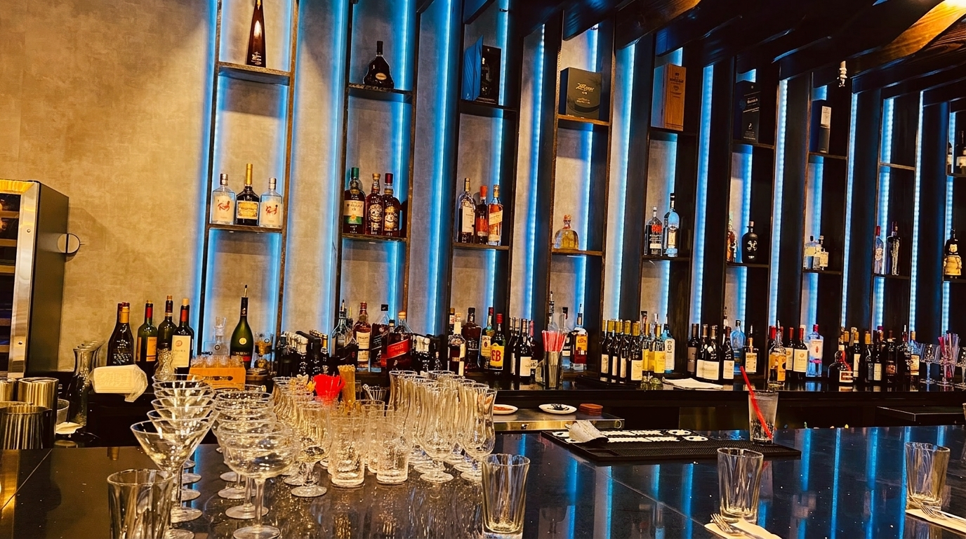 A well-stocked bar with various liquor bottles on shelves illuminated by blue LED lights.