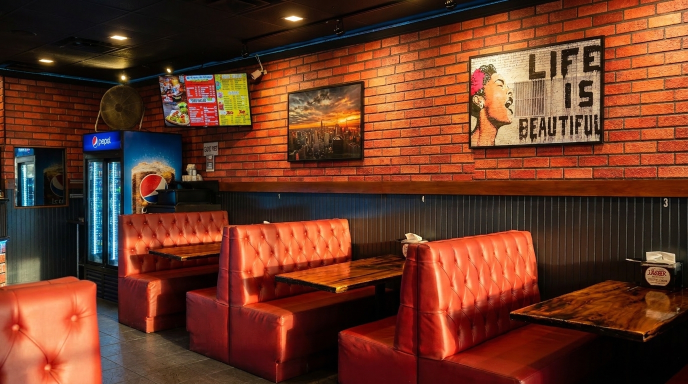 Interior of a restaurant with red booths, brick walls, and a menu board.