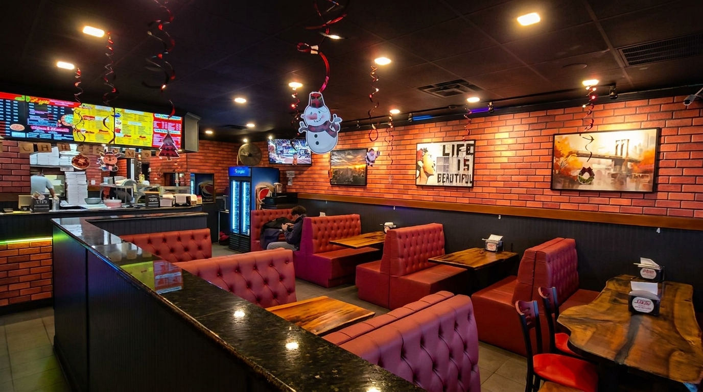 Restaurant interior with red brick walls, red booths, wooden tables, and holiday decorations.