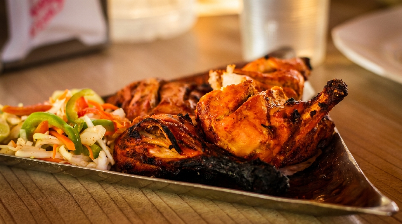 Grilled chicken pieces with crispy skin and a side of fresh vegetable salad on a silver platter.