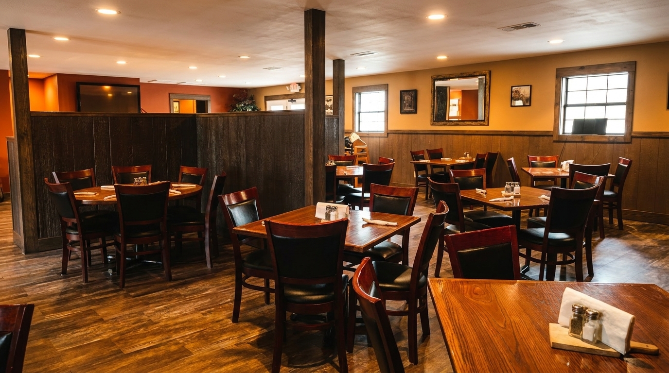 Warmly lit restaurant dining room with wooden tables, dark chairs, and wood-paneled walls.
