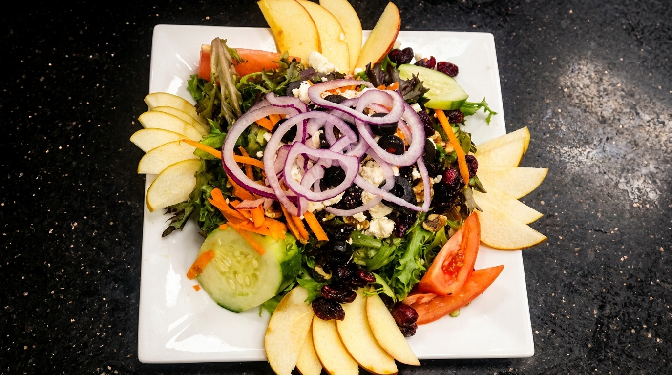 Fresh garden salad with mixed greens, red onions, apples, cucumbers, tomatoes, and cranberries.