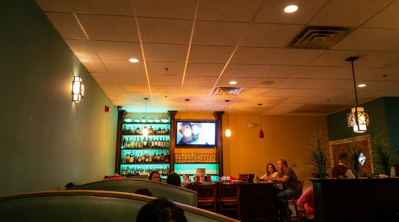 A restaurant interior with booths, a bar, liquor shelves, and patrons dining.