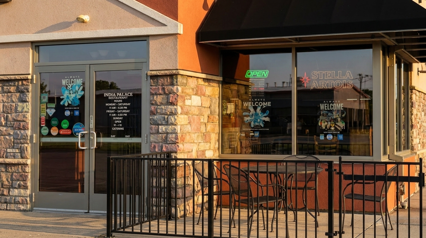 Exterior of India Palace Restaurant with a black awning, stone facade, and outdoor seating.