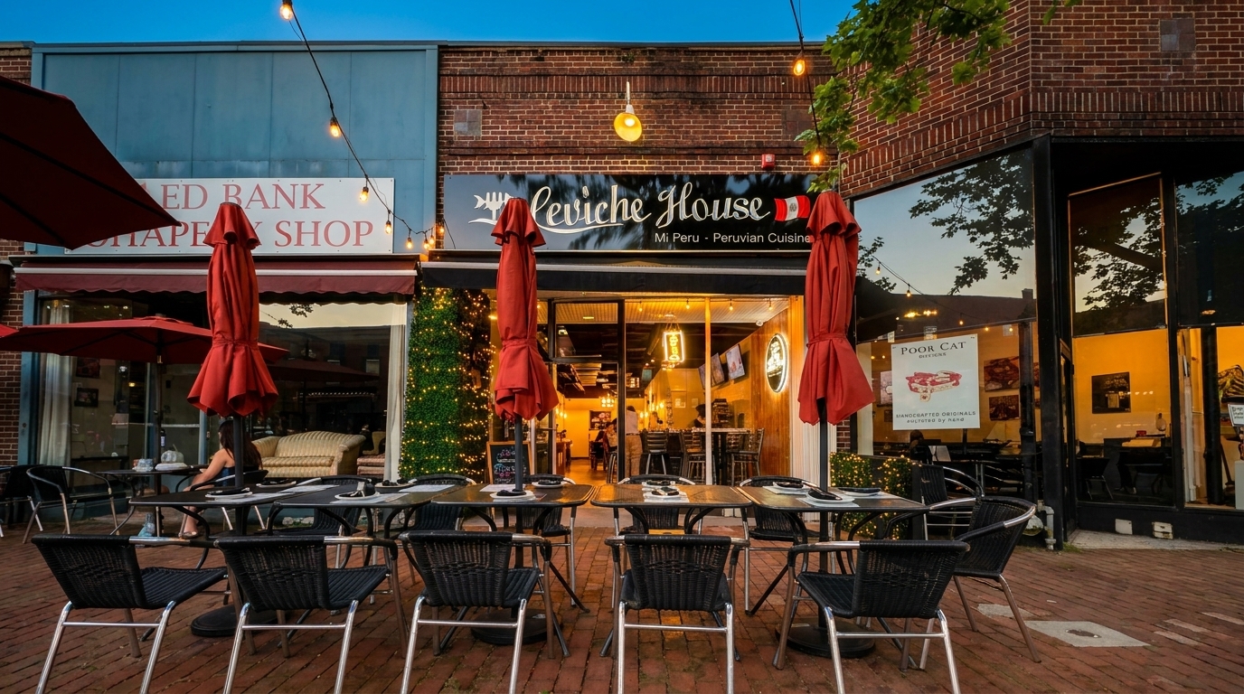 Outdoor patio seating with black tables and chairs in front of Ceviche House, a Peruvian restaurant.