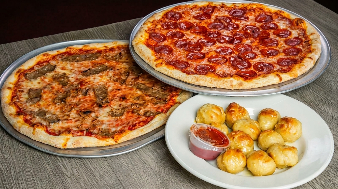 Two pizzas, one pepperoni and one with steak, alongside a plate of garlic knots with marinara sauce.
