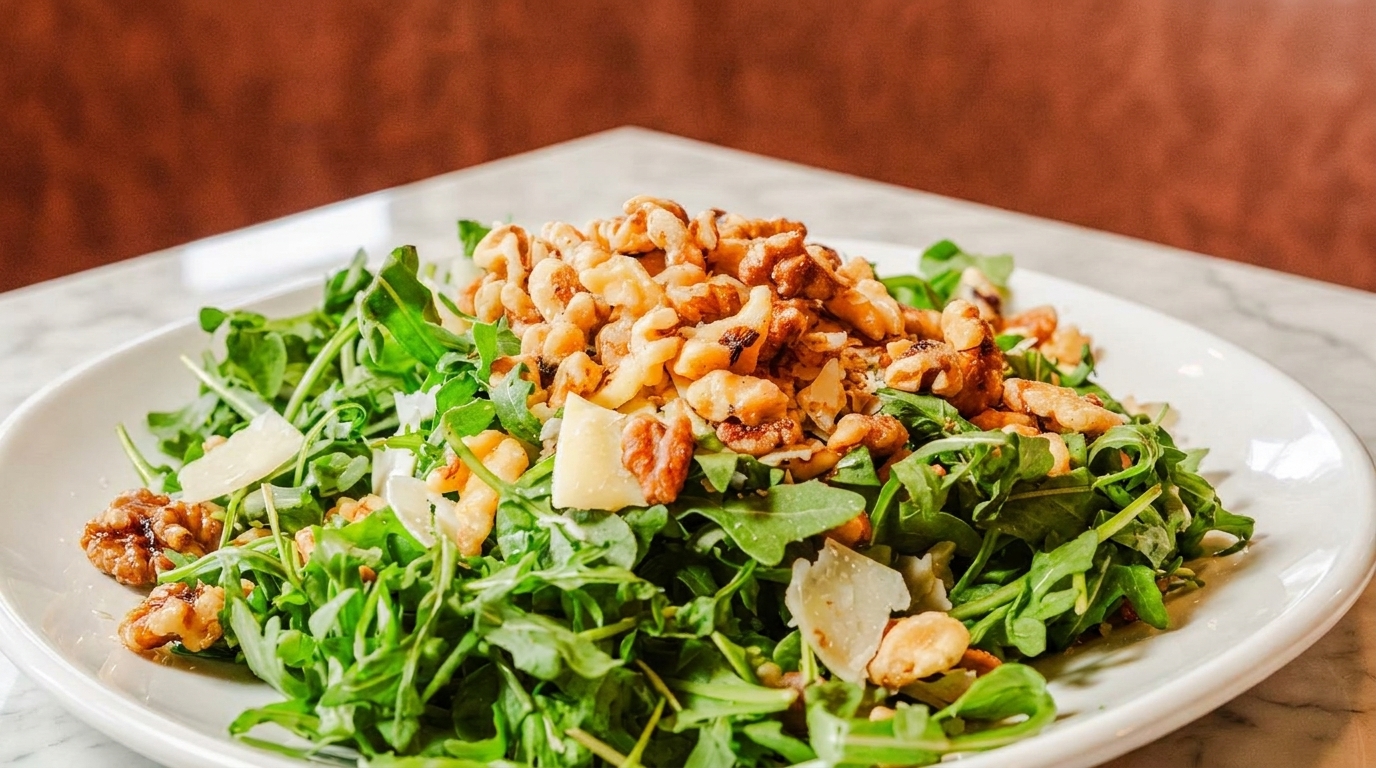 Arugula salad with walnuts and parmesan cheese on a white plate.