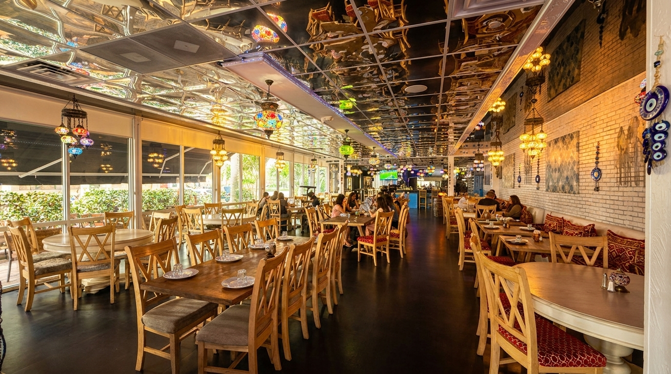 Spacious restaurant interior with wooden tables, chairs, ornate hanging lamps, and a mirrored ceiling.