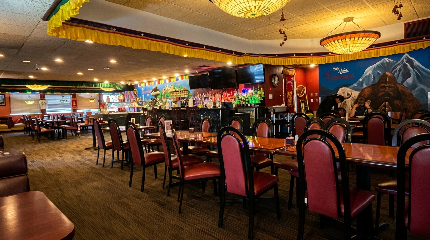 Interior of a restaurant with red chairs, wooden tables, a bar, and a mural of mountains and a yeti.