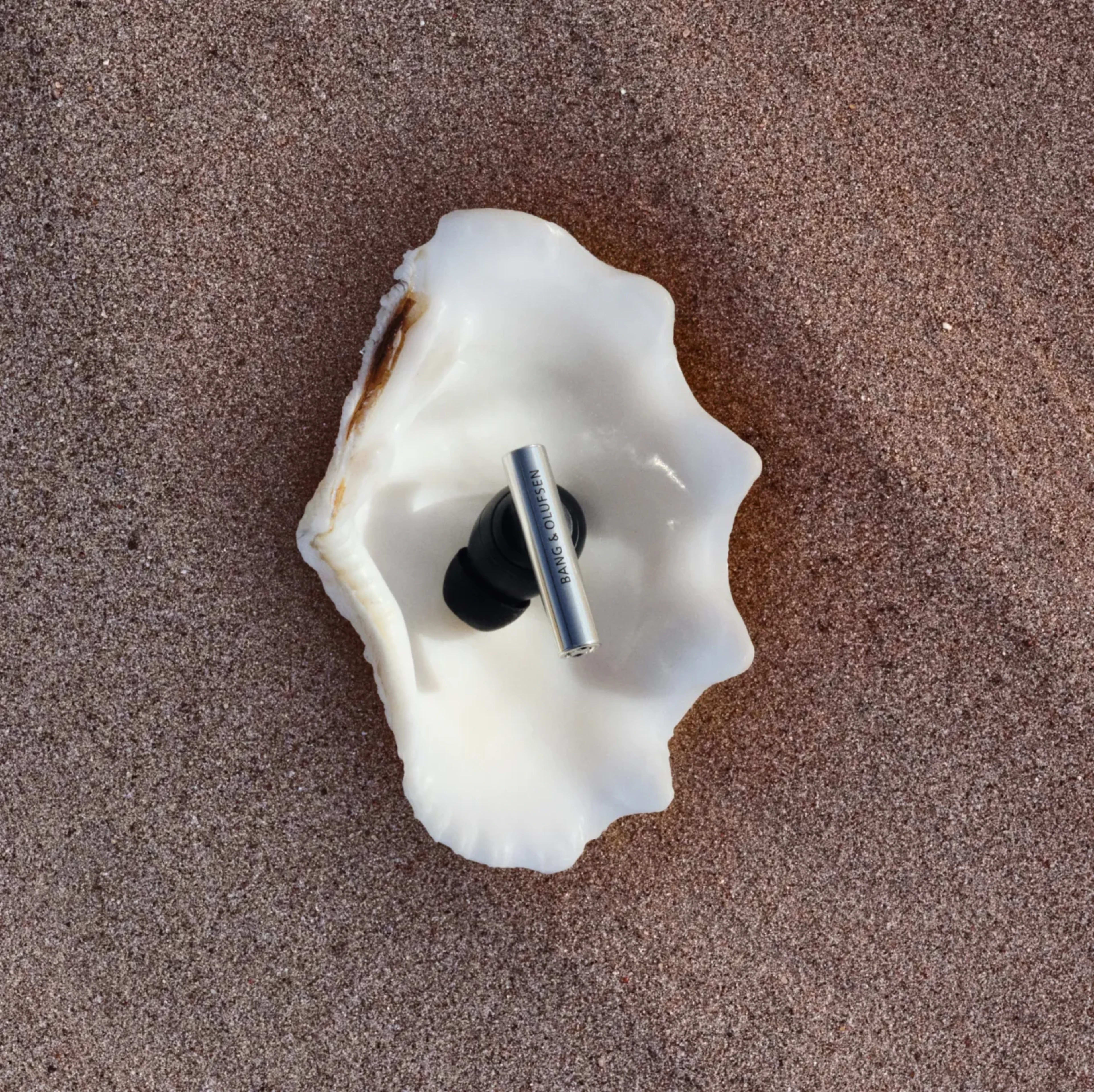 One of Super Hoodie earphone placed on a sea shell