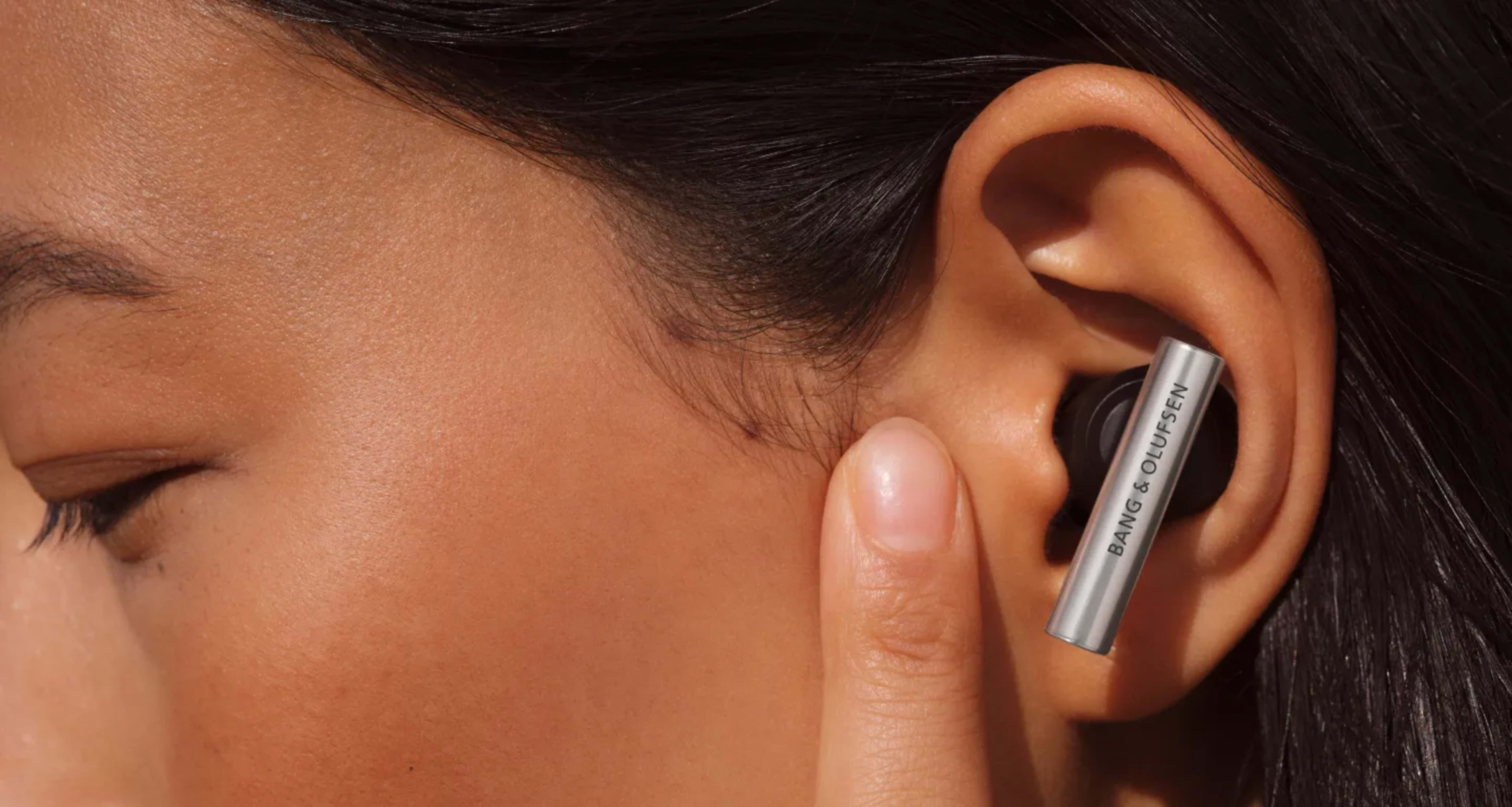 Super Hoodie plugged in an ear and a woman touching the skin in front of her ear