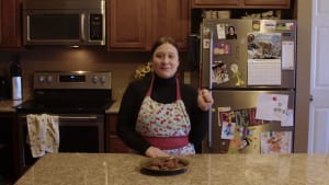 A woman in an apron with a plate of cookies.